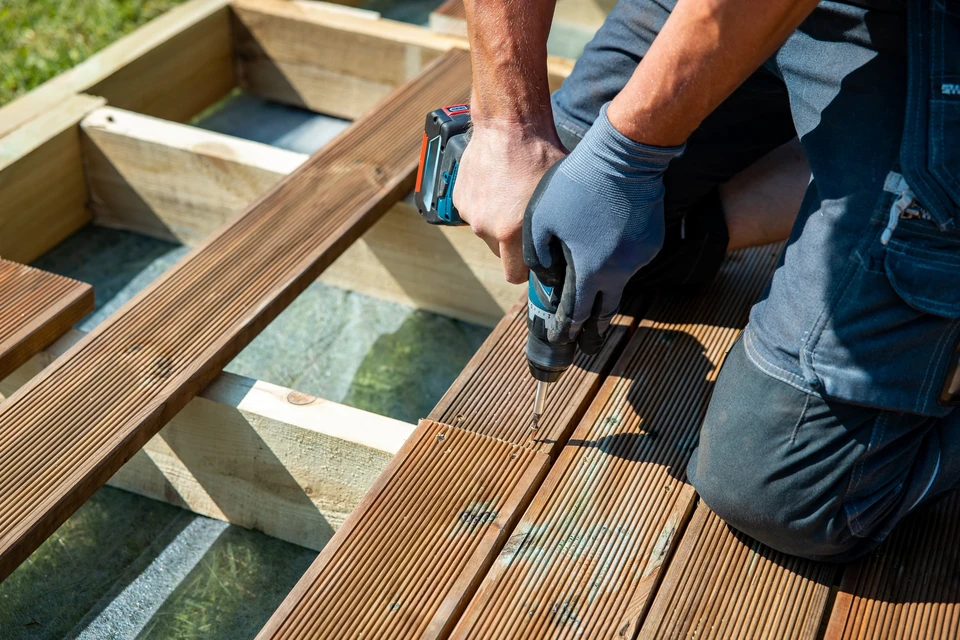 Ouvrier en vêtements de travail réalisant un assemblage de terrasse extérieure