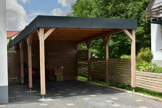 Espace extérieur couvert avec structure métallique noire supportant une toiture plate