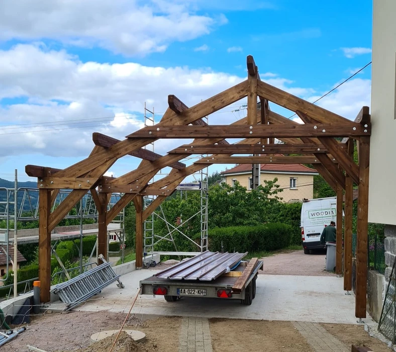 Terrasse extérieure aménagée avec pergola moderne en bois et acier, équipée d'un espace barbecue intégré et coin salon avec cheminée