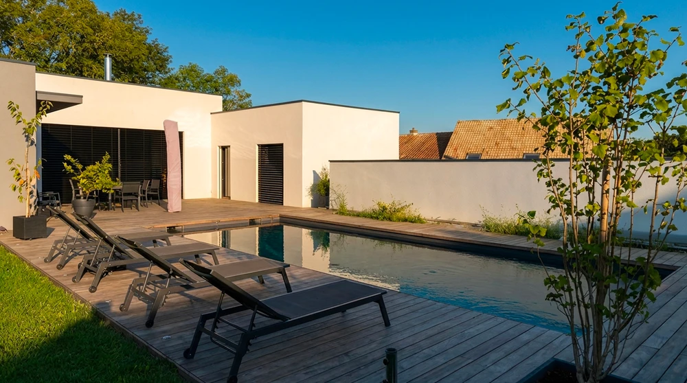 Terrasse en bois composite IPE, avec salon de jardin en résine tressée noire, deux chaises longues ergonomiques, table basse vitrée et boule lumineuse LED décorative
