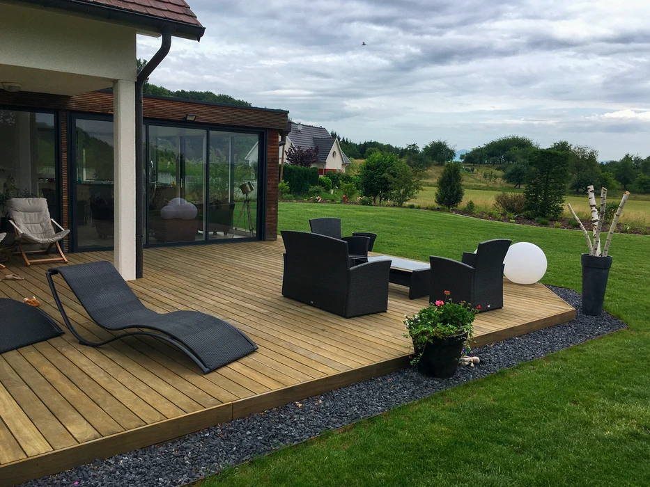 Piscine extérieure à débordement partiel avec terrasse en bois composite, entourée de végétation dense