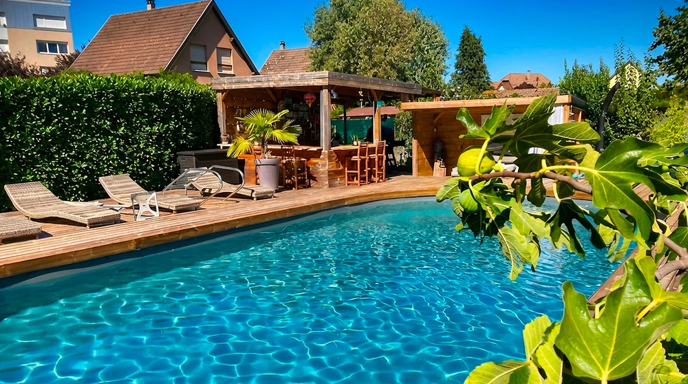 Piscine rectangulaire semi-enterrée à débordement, margelles en pierre calcaire beige