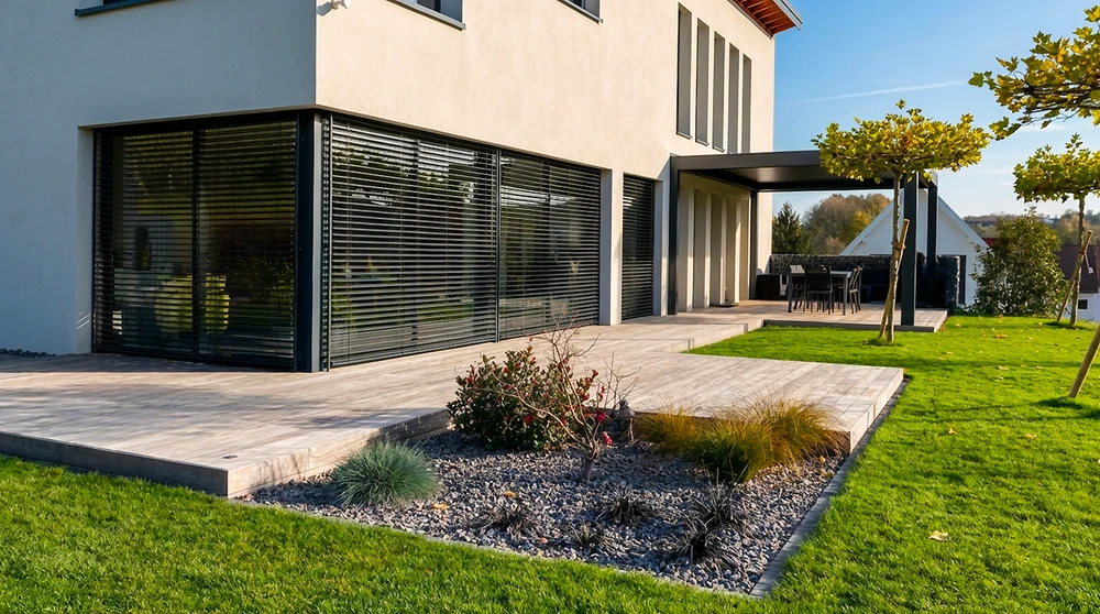 Piscine extérieure privée de forme ovale avec revêtement liner bleu, entourée d'une terrasse en bois composite IPE
