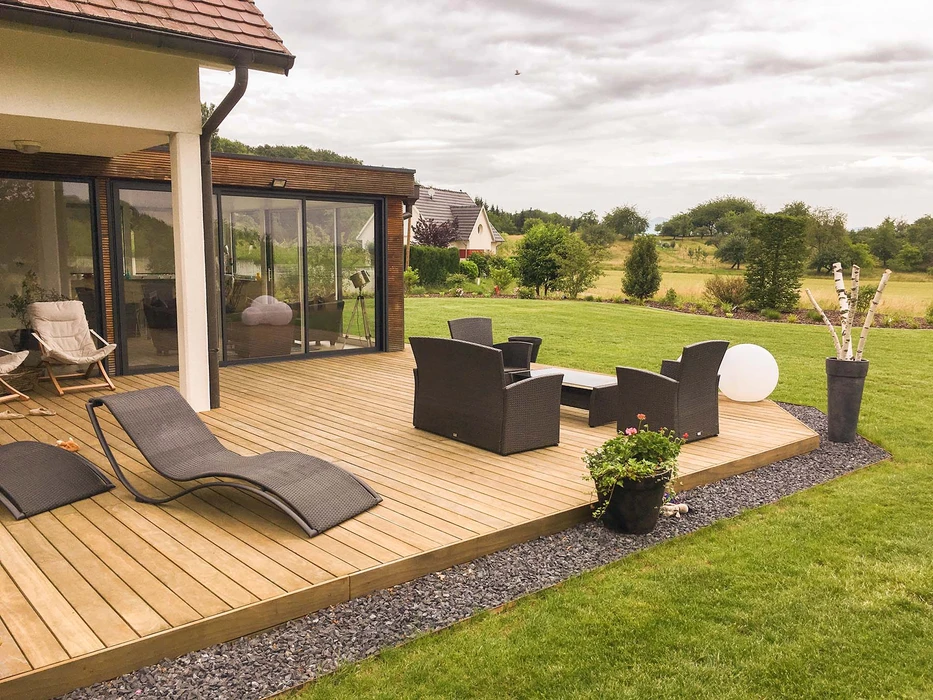 Terrasse de piscine privée extérieure, deux bains de soleil en aluminium anthracite avec textilène gris et appuie-tête, dallage en pierre calcaire beige