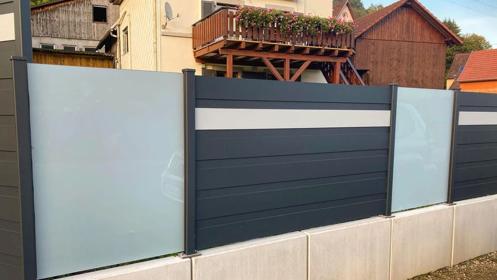 Pergola bioclimatique aluminium anthracite vue en plongée, toiture à lames orientables en position semi-ouverte créant un jeu d'ombres sur terrasse bois composite