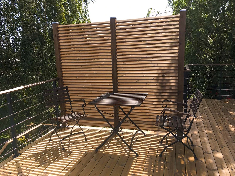 Pergola bioclimatique aluminium anthracite vue en plongée, toiture à lames orientables en position semi-ouverte créant un jeu d'ombres sur terrasse bois composite