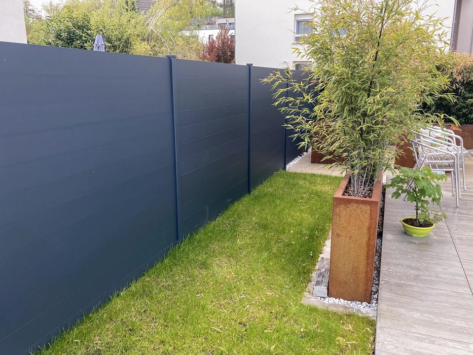 Pergola bioclimatique aluminium anthracite vue en plongée, toiture à lames orientables en position semi-ouverte créant un jeu d'ombres sur terrasse bois composite