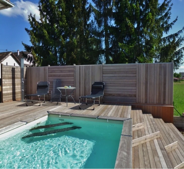 Pergola bioclimatique aluminium anthracite vue en plongée, toiture à lames orientables en position semi-ouverte créant un jeu d'ombres sur terrasse bois composite
