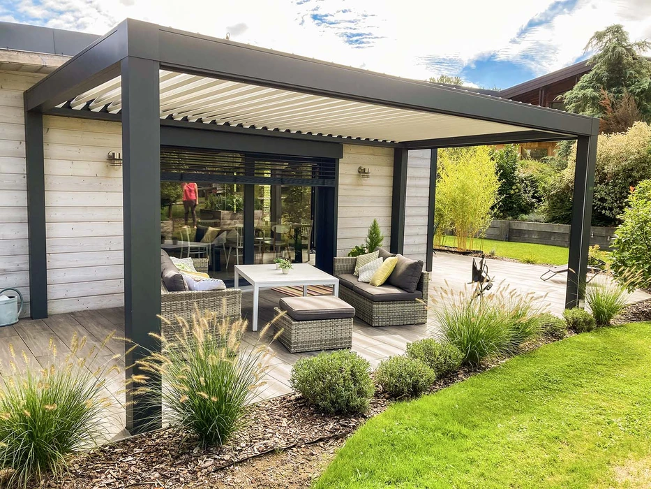 Terrasse extérieure avec mobilier de jardin en résine tressée naturelle : deux fauteuils daybed ovales et une table basse cylindrique