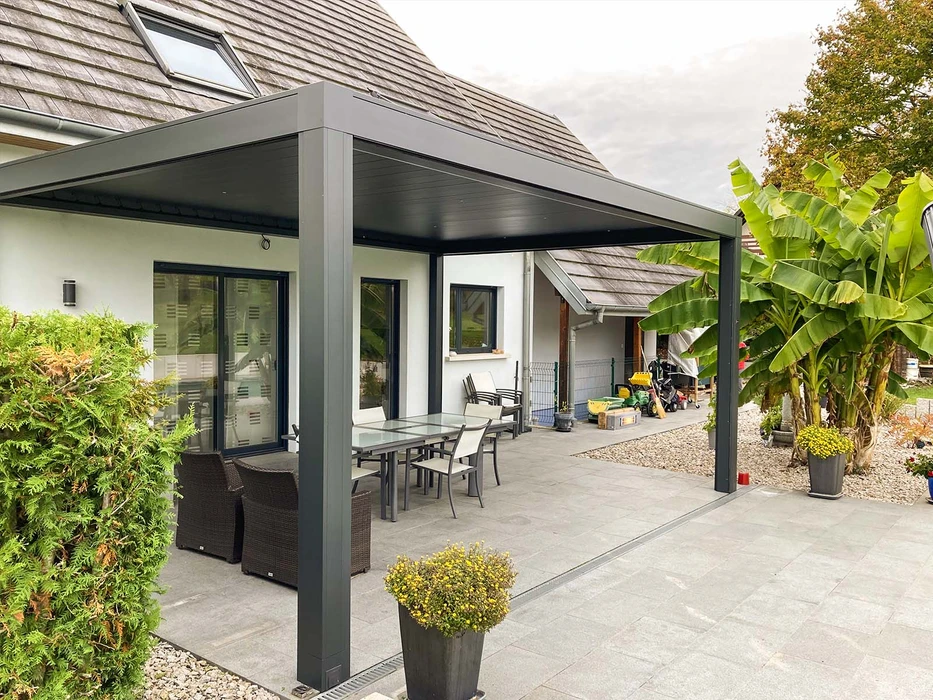 Terrasse extérieure avec mobilier de jardin en résine tressée naturelle : deux fauteuils daybed ovales et une table basse cylindrique