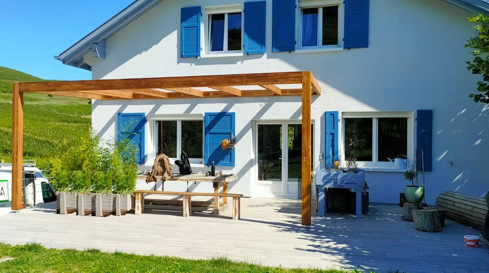 Piscine rectangulaire à débordement avec margelles en terrasse bois composite, entourée de transats noirs en aluminium et textilène