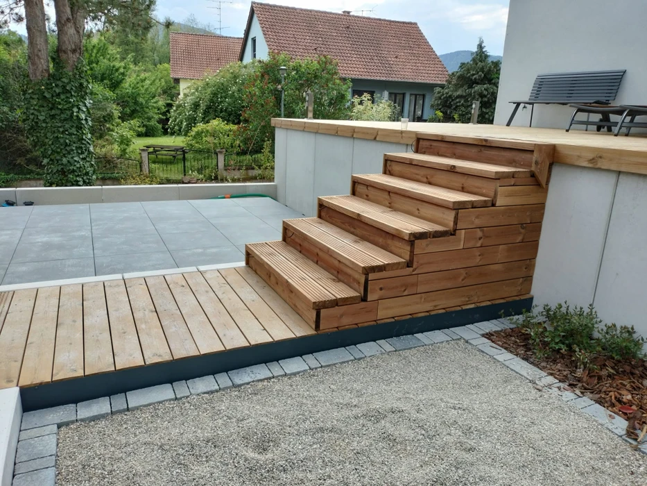 Terrasse en bois extérieure surélevée avec vue panoramique sur prairie verdoyante et forêt automnale